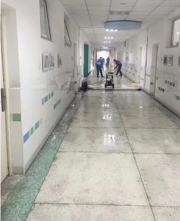Klinikflur vor der Grundreinigung: stumpfer, fleckiger Boden, im Hintergrund läuft die Maschine.